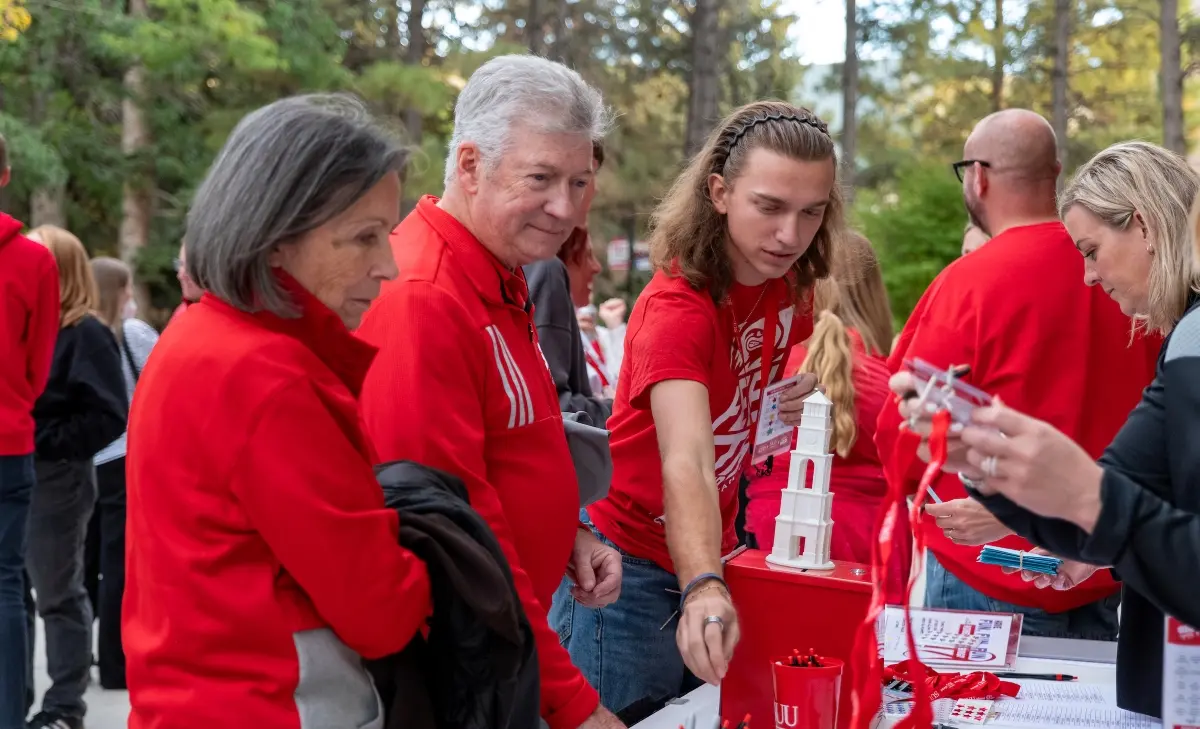 A retired SUU employee walking across a street while holding the hand of a young girl
