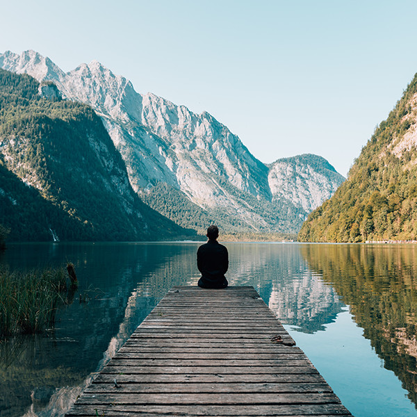 Person sitting on pier in mountains