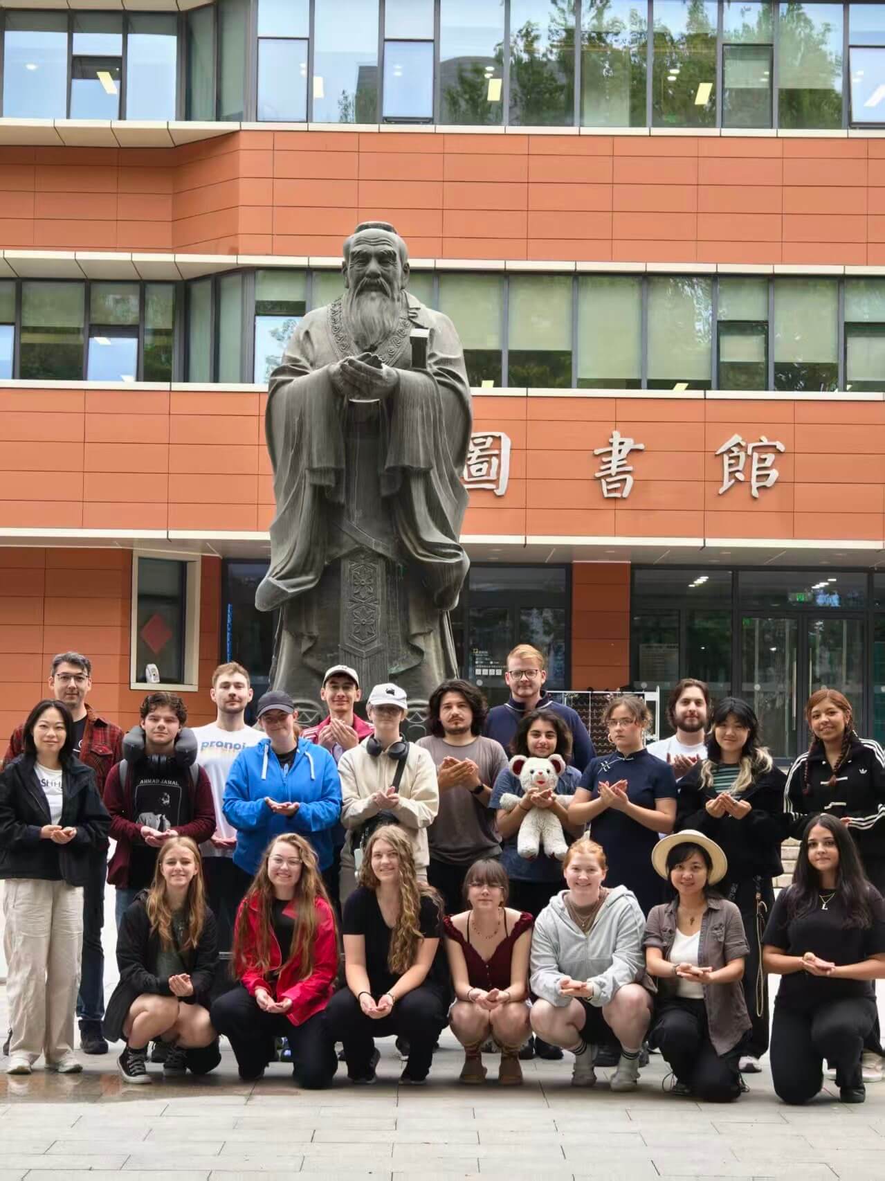 A group of study abroad students posing with a statue of Confucius in front of the BLCU Library 3