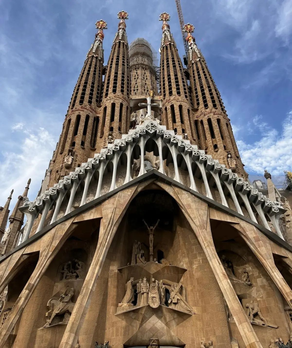 A view looking up at the enormous grandeur of the Sagrada Familia Bastille in Barcelona Spain. The gigantic structure's impressive architecture boasts incredibly detailed sculptures, huge curved arches and towering spires. 1