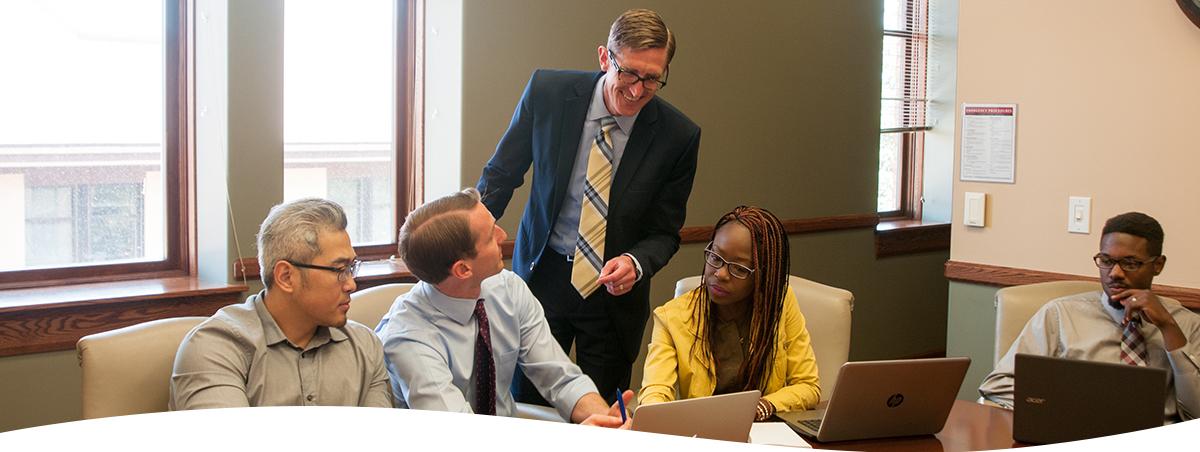 This image contains 5 people around a table in professional garb.