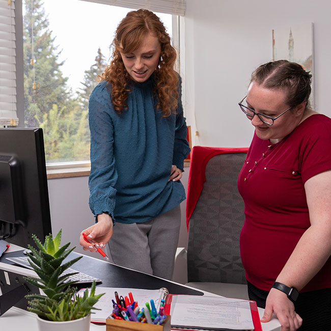 Image of two female students collaborating over a notebook