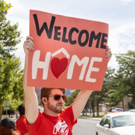 Student holding Welcome Home Sign