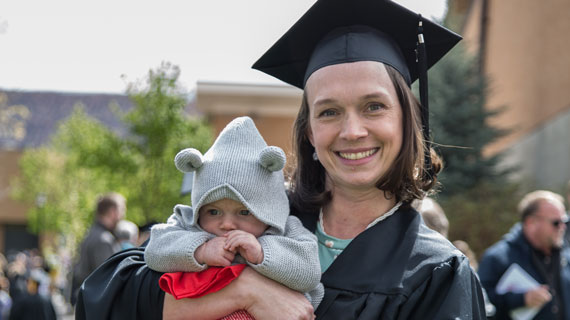 SUU graduating senior with child mom graduates with degree cap and gown baby