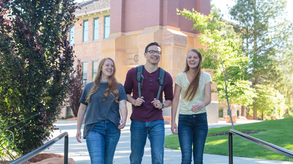 3 students walking on SUU's campus by the Bell Tower