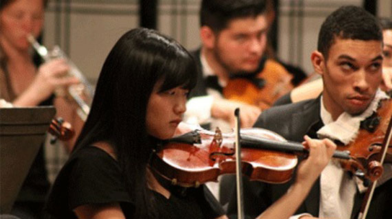 Student performing the violin in a symphony orchestra at SUU