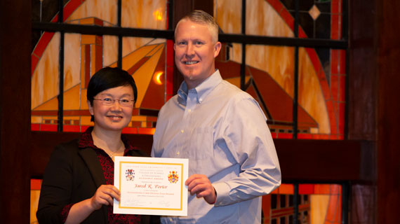 Dezhi Wu with student Jared Porter holding an award for outstanding member of the Cyber Defense Club.