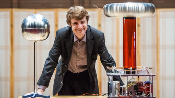Physics professor Brandon Wiggins smiling with Tesla Coil