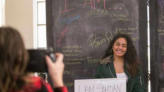 Student holding a sign stating "I am samoan" for a picture