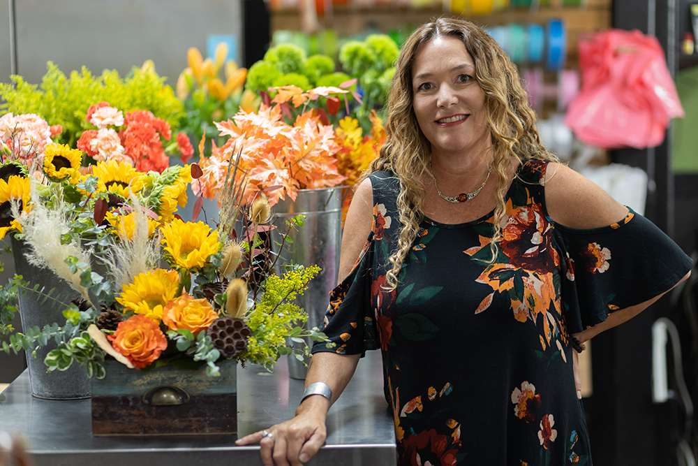Woman posing in front of a floral arrangment