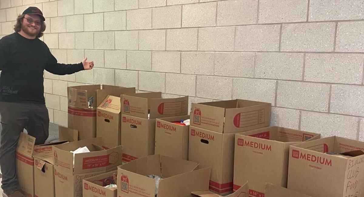 Student stands by boxes full of food