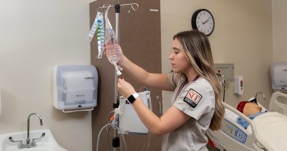 A nursing student in a clinic filling an I.V. bag