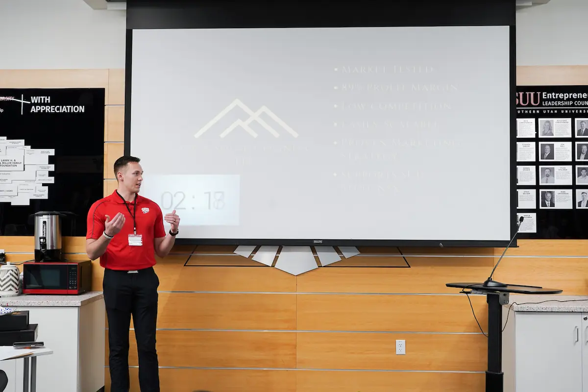 Presenter in SUU red at the Business Breakthrough in front of projection screen