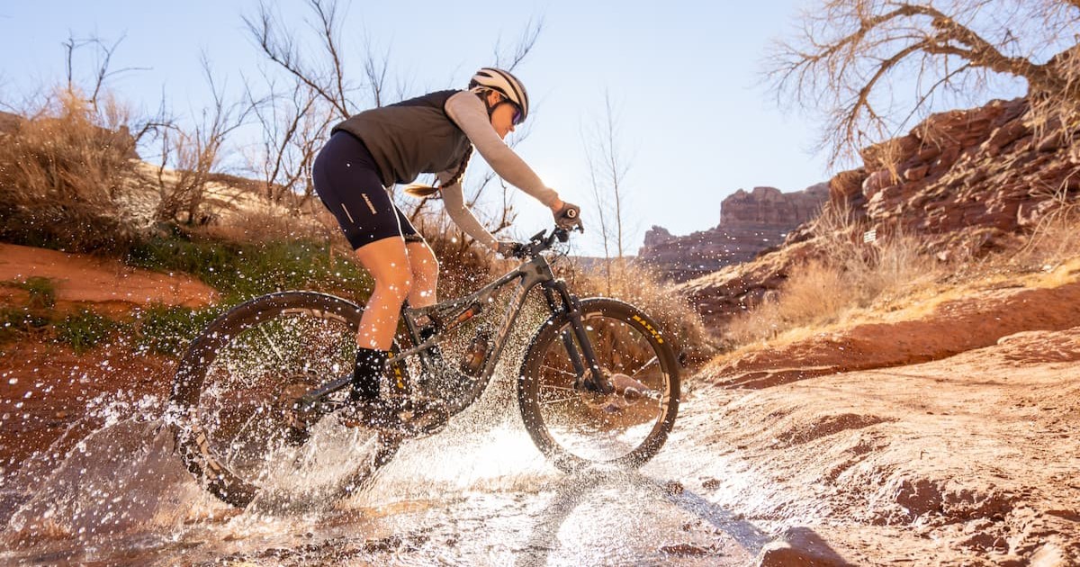 A man riding a mountain bike through a shallow stream