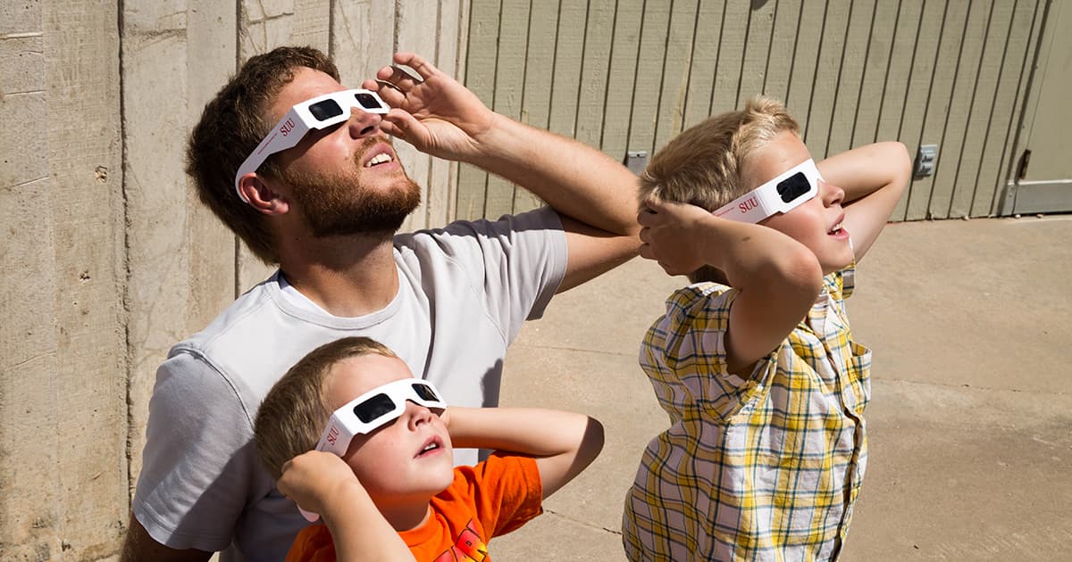 People viewing a solar eclipse wearing special SUU eclipse glasses.
