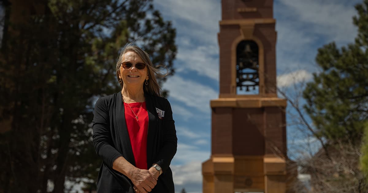 Rita Osborn standing in front of the SUU bell tower. 