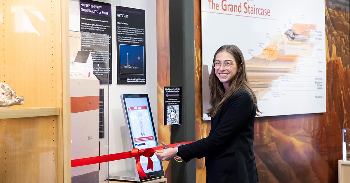 A young woman cuts a ribbon wrapped around new exhibit. 