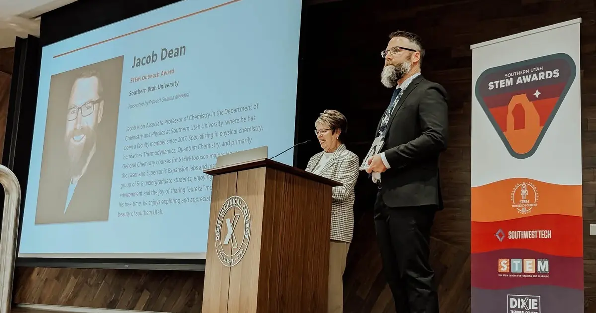 Dr. Jacob Dean stands on a stage to accept the award. 