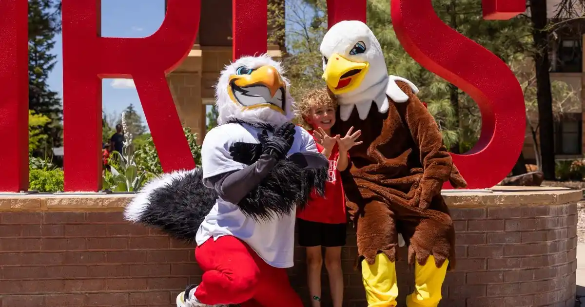 East Elementary student poses with Eagle and T-bird mascots