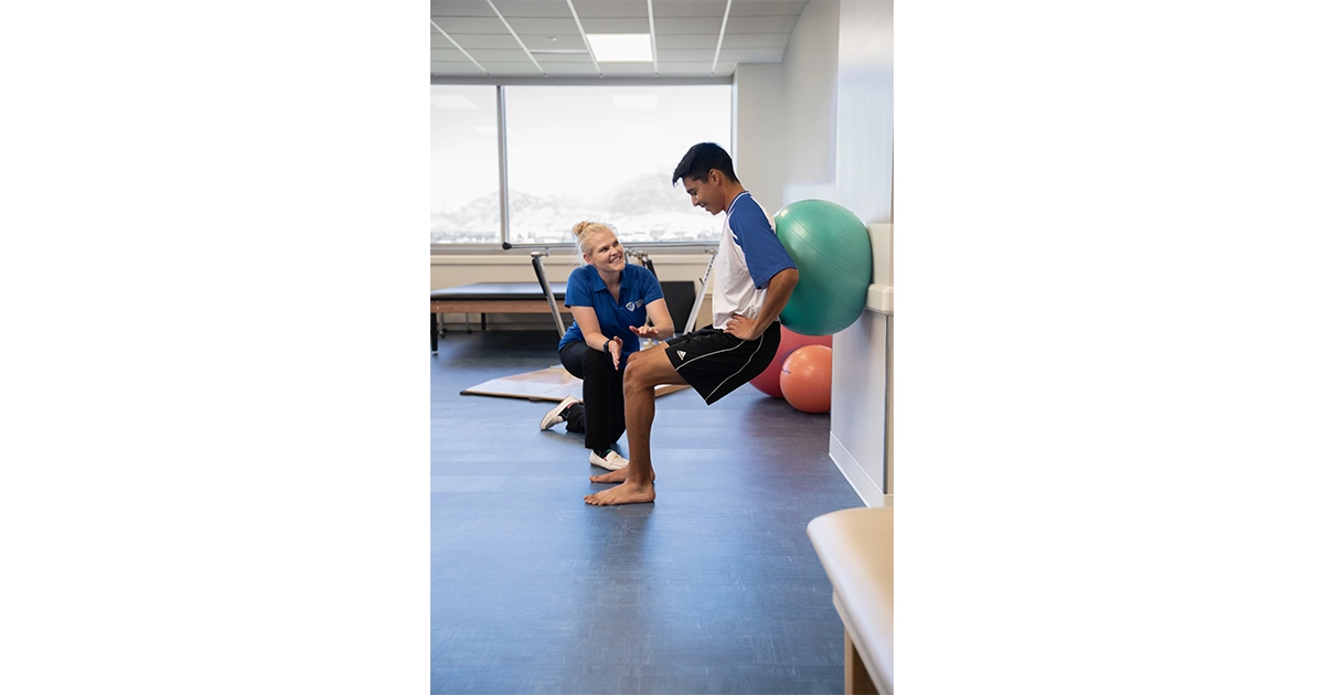 A healthcare professional guides a man through an exercise.