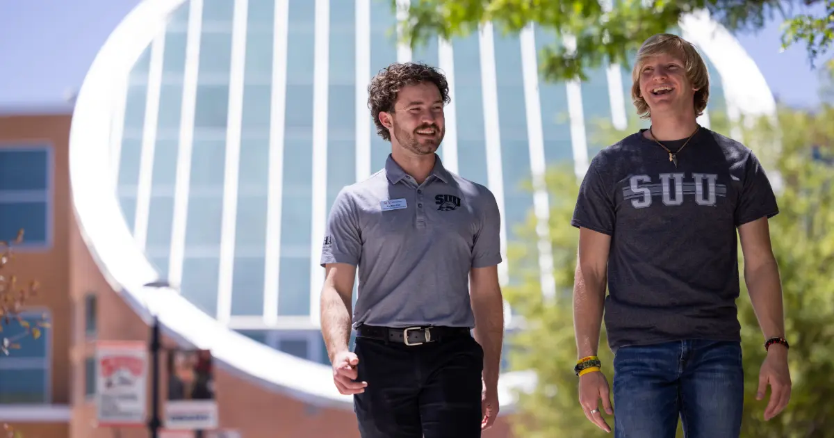 Two males walking and smiling on SUU campus.