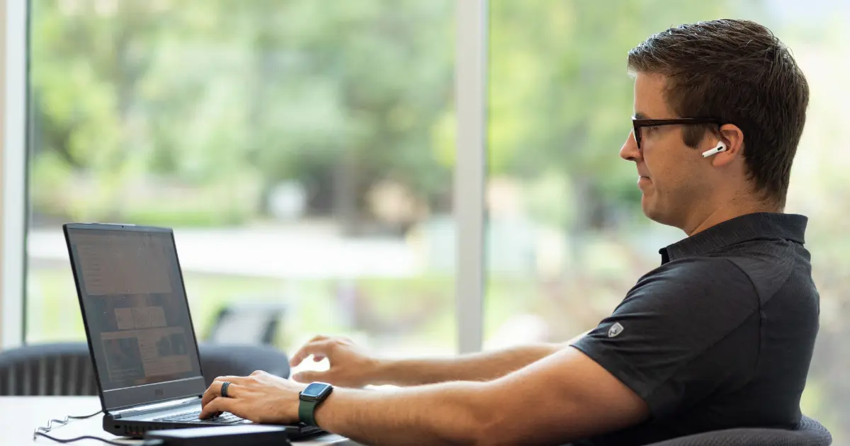 Student in glasses looking at laptop.