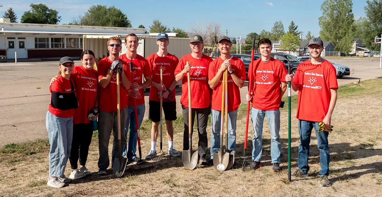 A group of volunteers stand in line and smile at the camera.