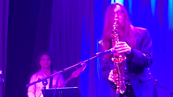 A student playing saxophone on a stage.