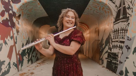 Photo of Megan Rasmussen. She holds a flute in a tunnel.