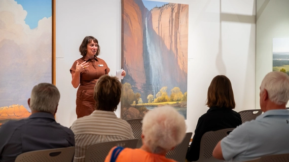 Dr. Bloom presents to patrons at SUMA near Jimmy Jones landscape paintings.