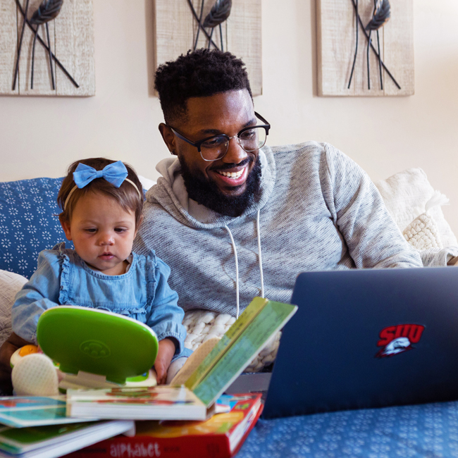 Father on Laptop with baby on bed
