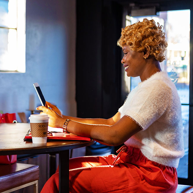 Woman sitting at desk looking at cell phone for the adult learner grant at suu.