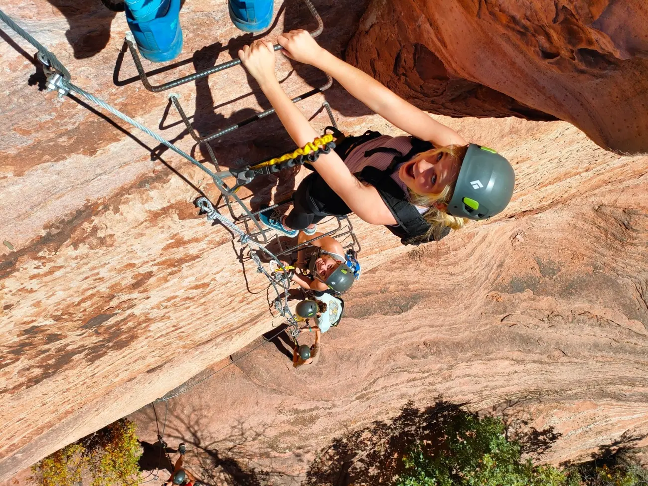 A girl climbing up a set of ladder steps on a cliff face 1