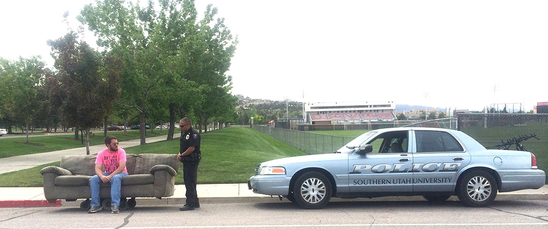 An SUU Police officer talking to a person driving a motorized couch.