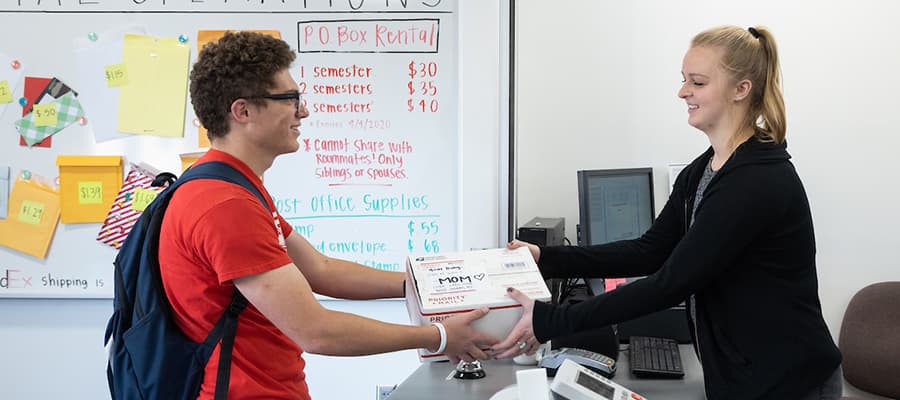 Student getting a package from a post office employee