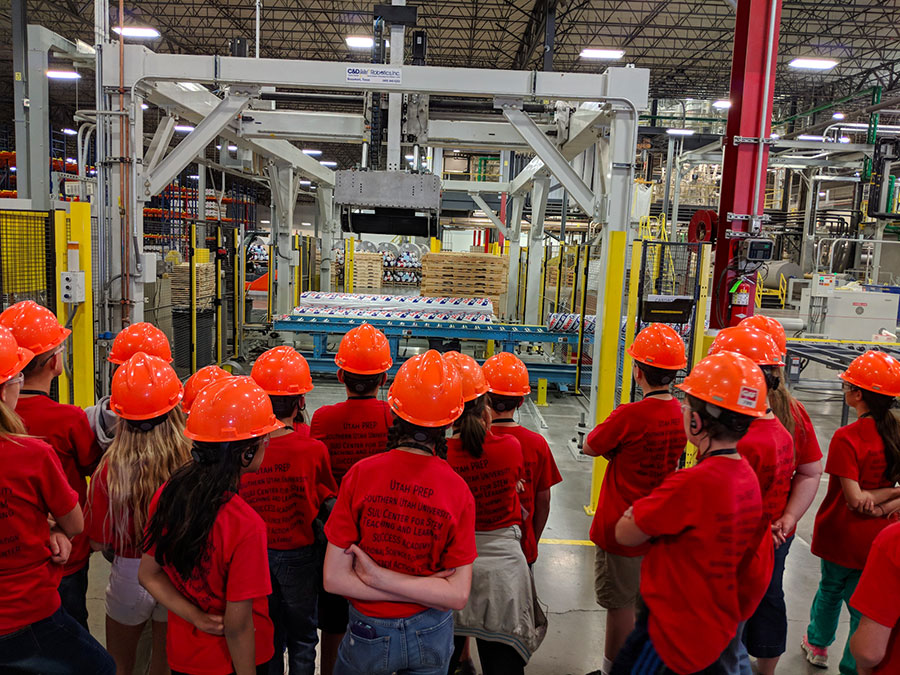 Students wearing hard hats on a tour of a manufacturing plant