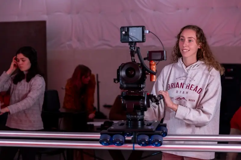 SUU student operating a camera setup, while other students are behind monitoring other aspects of a film set.