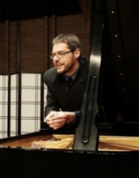Dr. Christian Bohnenstengel leaning on a piano.