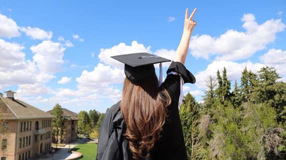 Student holding a piece sign in the air on graduation day