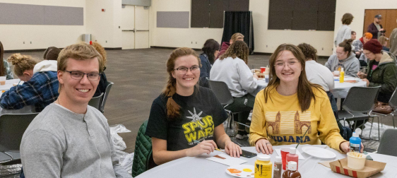 An image of some SUU students sitting at a table smiling.