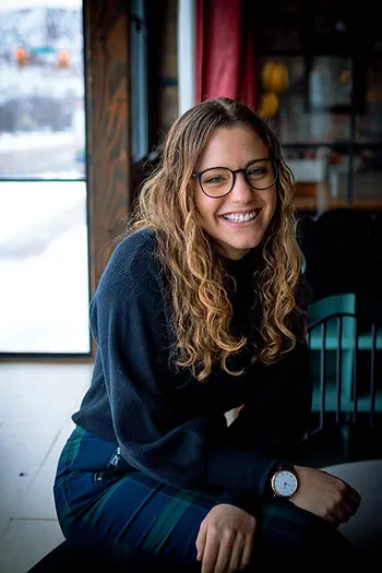 A photograph of Ansleigh smiling while sitting on a bench.