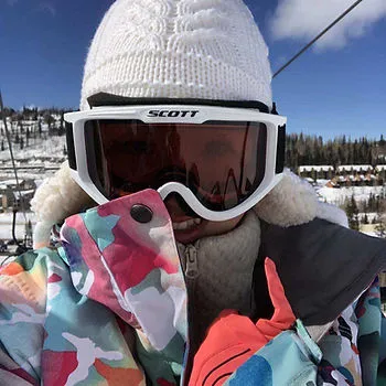 A selfie of a woman wearing lots of winter and ski gear. A ski lift is visible in the background. 