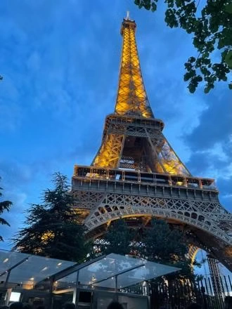 The Eiffel Tower lit in gold against a deep blue evening sky.