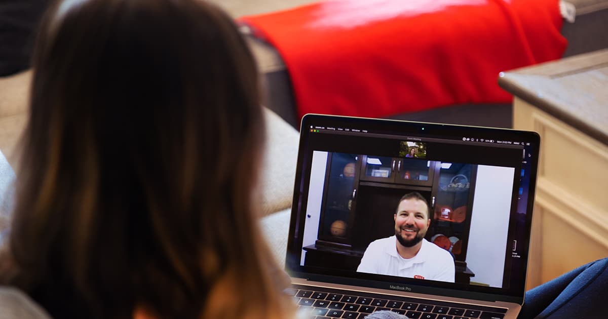 An online student video-chats on a laptop
